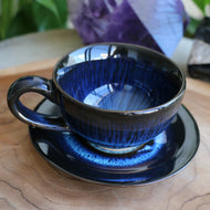 Handmade ceramic cup and saucer set with blue reactive glaze