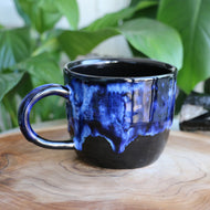 Handmade ceramic mug thats black with galaxy-like blue drip gaze and large handle