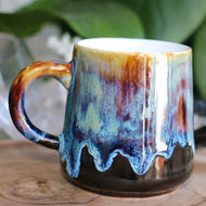 Handmade ceramic mug with a medium handle, featuring a brown color with a light blue drip glaze.